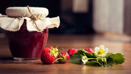 Homemade strawberry jam (marmelade) in jars on wooden background.の写真素材
