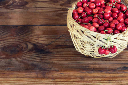 Ripe organic homegrown cherries in a basket, on wooden backgroundの写真素材