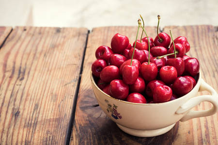 Ripe organic homegrown cherries in a vintage ceramic bowl, on wooden backgroundの写真素材