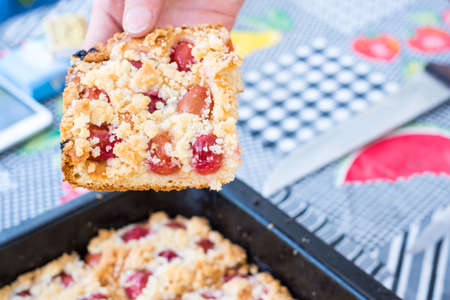 Hand taking a piece of sweet homemade cherry pie with crumble