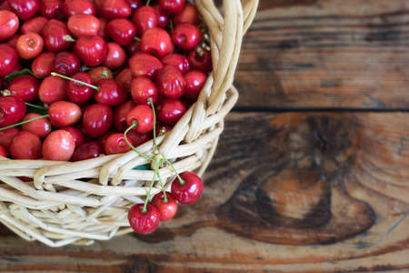 Ripe organic homegrown cherries in a basket, on wooden backgroundの写真素材