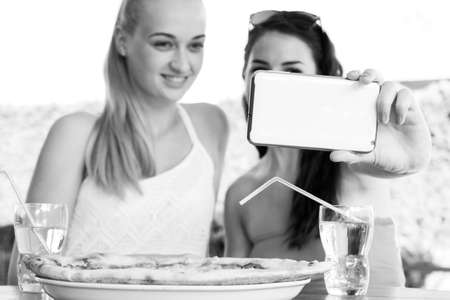Two attractive female friends taking a selfie with smartphoneの写真素材