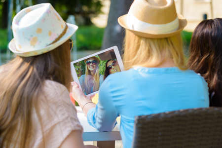 Three attractive hipster girls taking a selfie with digital tablet, back viewの写真素材