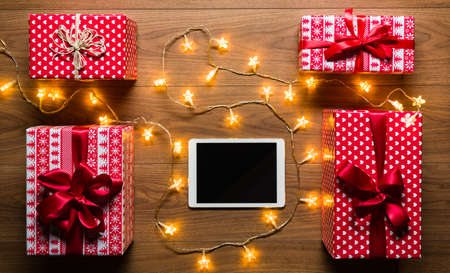 Desk view from above with digital tablet, presents and christmas lights, retro xmas concept with copy spaceの写真素材