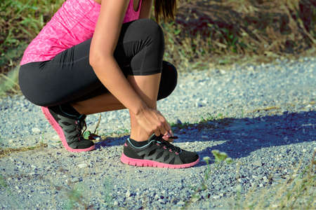 Attractive female runner tying her shoe laces