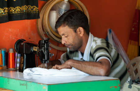 Goa, India - January 2008 - Local tailor making some quick alterations at his tiny shop, Baga, Goaのeditorial素材