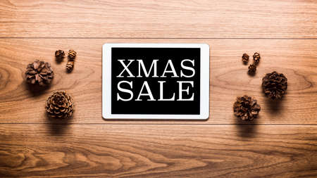 Magical christmas sale theme background, pine cones and digital tablet on wooden tableの写真素材