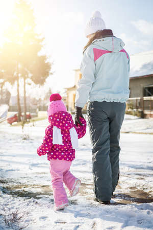 Mother and daughter walking together holding hands on a snowy winter dayの写真素材