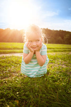 Adorable blond little girl with cheeky smile, outdoors play timeの写真素材