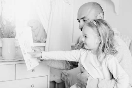 Cute blond girl giving her father a drawing, fathers day conceptの写真素材