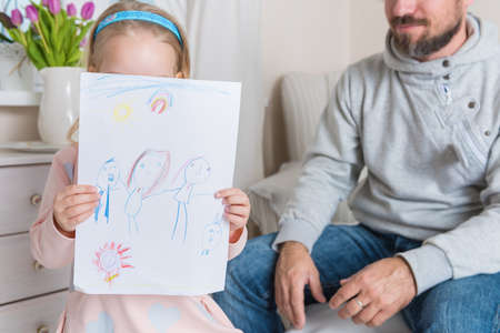 Cute blond girl giving her father a drawing, fathers day conceptの写真素材