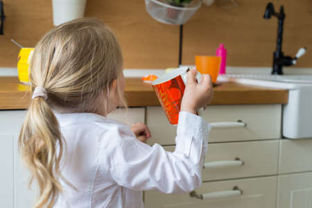 Cute blond girl holding a large cup of tea in the kitchenの写真素材