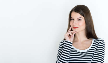 Attractive young woman deep in her thoughts, on white backgroundの写真素材
