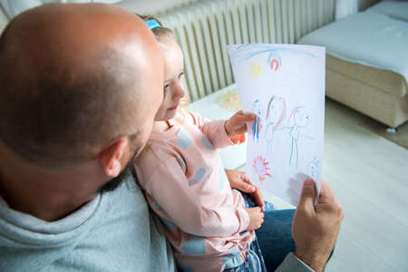 Cute blond girl giving her father a drawing, fathers day conceptの写真素材