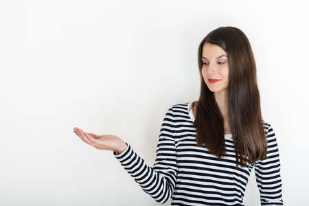 Girl showing empty copy space on open hand palm for text or product, white background. Smiling girl presenting point. Proposing product. Advertisement gestureの写真素材