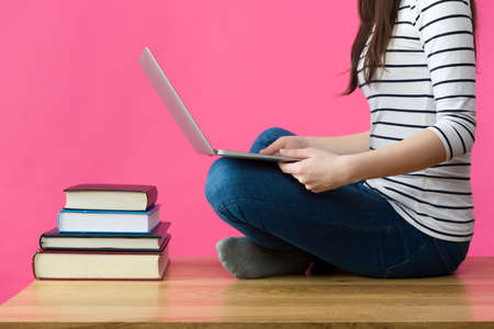 Attractive caucasian girl studying for her exams at home, student sitting on her desk with laptop in her lapの写真素材