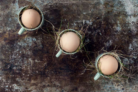 Uncolored natural easter eggs in green espresso cups, happy easter concept, retro easter backgroundの写真素材