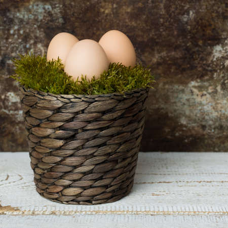 Three Easter eggs in a moss basket, happy easter concept, retro Easter backgroundの写真素材