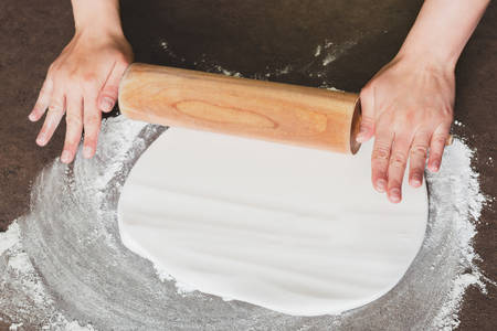 Woman using rolling pin preparing royal icing for cake decorating, hands detailの写真素材