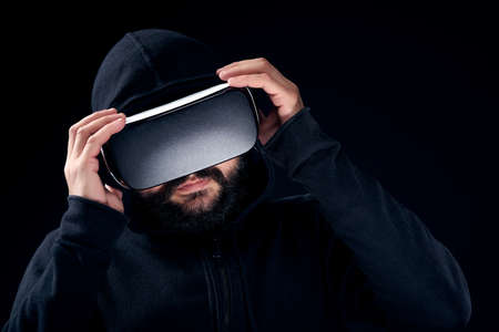 Young hipster bearded man wearing virtual reality goggles. Black background studio VR conceptの写真素材