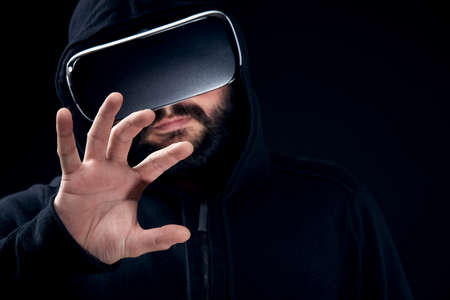 Young hipster bearded man wearing virtual reality goggles. Black background studio VR conceptの写真素材