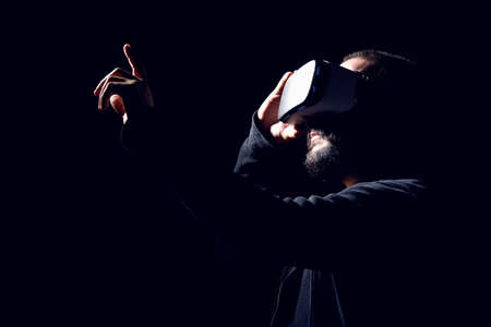 Young hipster bearded man wearing virtual reality goggles. Black background studio VR conceptの写真素材