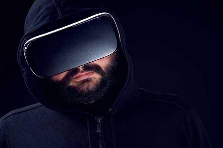 Young hipster bearded man wearing virtual reality goggles. Black background studio VR concept.の写真素材
