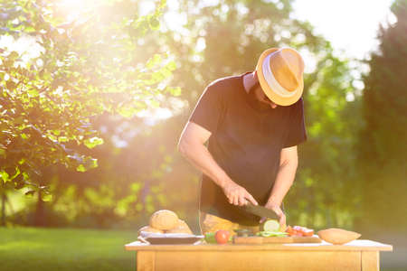 Young hipster man preparing food for garden grill party, summer barbecue conceptの写真素材