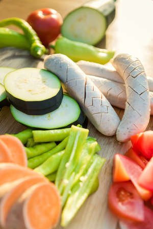 Freshly cut vegetables and sausages on a cutting board, bbq summer garden food conceptの写真素材