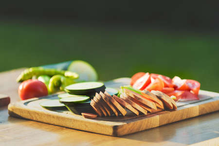 Freshly cut vegetables and sausages on a cutting board, bbq summer garden food conceptの写真素材