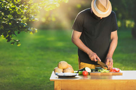 Young hipster man preparing food for garden grill party, summer barbecue conceptの写真素材