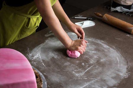Unrecognisable woman preparing pink fondant for cake decorating, hands detailの写真素材