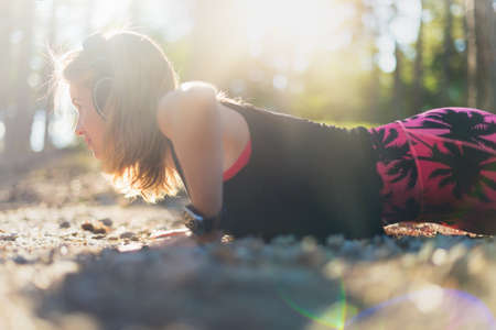 Lifestyle wearable technology shot with lensflare. Female athlete wearing smart watch doing push upsの写真素材