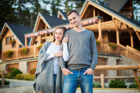 Young attractive married couple standing outside their large wooden cottage in the woods.の写真素材