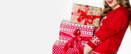 Gorgeous woman in christmas jumper holding loads of heavy xmas presents, christmas banner, isolated on white backgroundの写真素材