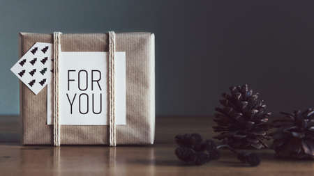 Retro, natural and simple xmas home decoration with beautiful window light. Wrapped Christmas Present on a tableの写真素材