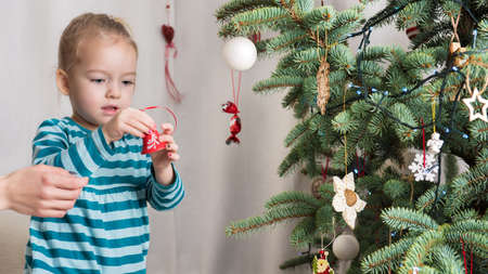 Cute blond preschool girl decorating christmas tree. Authentic family xmas time conceptの写真素材