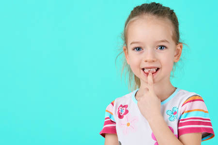 Adorable little girl smiling and showing off her first lost milk tooth. Cute preschooler portrait after dropping her front baby tooth.の写真素材