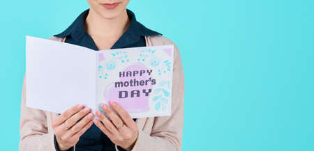 Anonymous young single mother reading mother's day card. Happy Mother's Day Concept.の写真素材