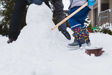 Authentic family winter fun. Family building a snowman in their frontyard. Candid real people...