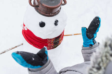 Authentic family winter fun. Young child building a snowman. Candid real people lifestyle image of making a snowman.の写真素材