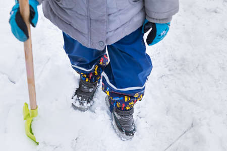 Child helping clearing snow from sidewalk. Candid authentic family winter activities. Snow shoveling...