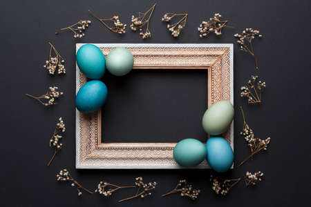 Happy Easter rustic background with copy space. DIY dyed various shades of blue Easter eggs and vintage wooden picture frame mock up.の写真素材