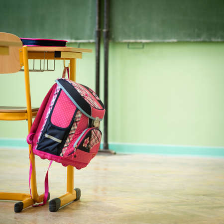 Pink girly school bag and pencil case on a desk in an empty classroom. First day of school concept.の写真素材