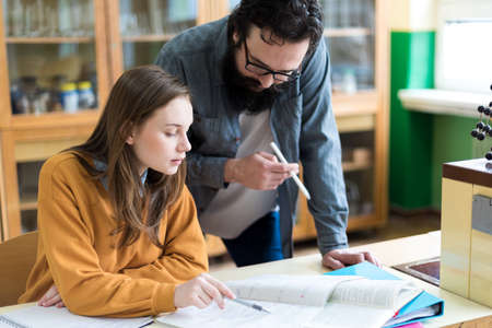 Young teacher helping his student in chemistry class. Education, Tutoring and Encouragement concept.の写真素材