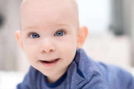 Adorable baby boy with blue eyes looking directly at camera trying to reach for it. Cute toddler...