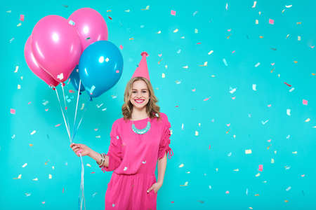 Gorgeous birthday girl in party outfit holding colourful balloons. Attractive trendy teenager...