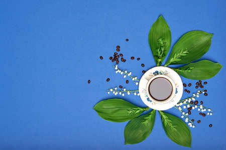 Cup of black coffee with flowers on blue coloured art background. Good Morning coffee floral setup...