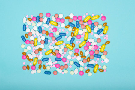 Assortment of various colourful pills on pastel coloured background. Medication and prescription...
