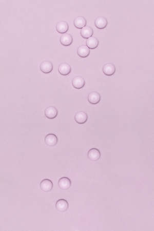 Pale pink pills on pastel colored pink background. Medication and prescription pills minimal...